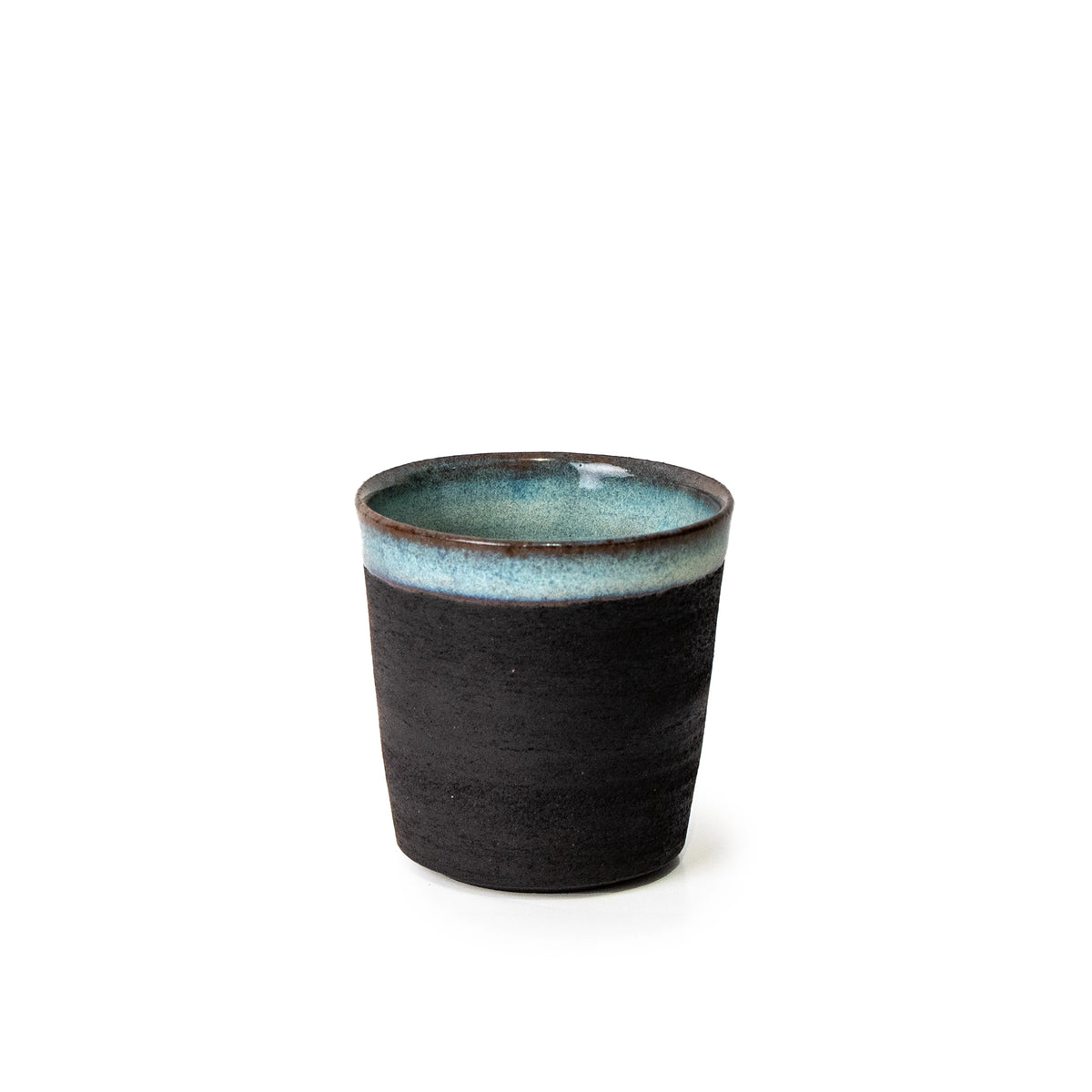 De AB Ceramics Beker Zwart Opaal 20 cl is een handgemaakte beker van zwart steengoed klei met matte buitenkant en glanzend blauwgroen glazuur, gemaakt in Antwerpen door AB Ceramics en gefotografeerd tegen een witte achtergrond.