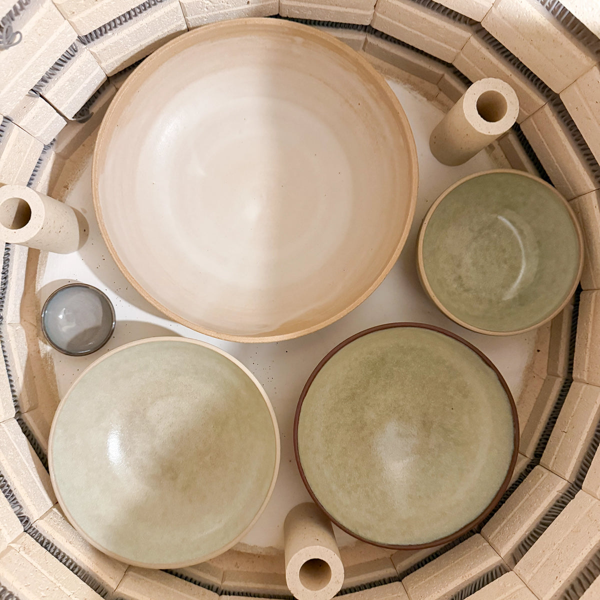 Vier unieke AB Ceramics Noodle Kom Wit Mint D19 kommen - drie mint, één wit - staan opgesteld in een ronde oven. Elk handgemaakt stuk van AB Ceramics varieert in grootte en is ideaal voor noedels of het serveren van je favoriete gerechten.