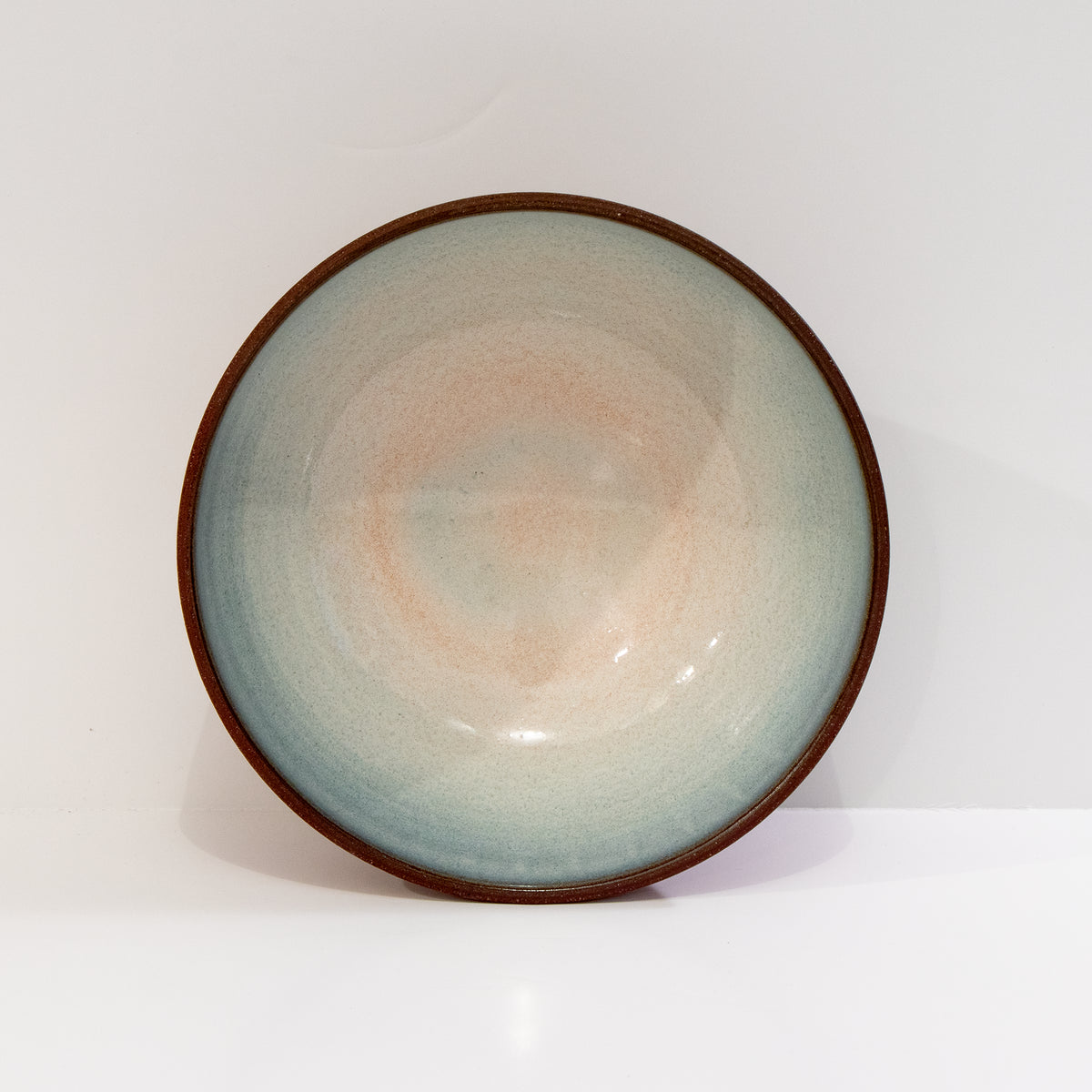 De AB Ceramics Kom Rood Opaal D18 van AB Ceramics is een handgedraaide ronde schaal van keramiek met een glanzend rode opalen afwerking, geaccentueerd door een donkere rand en afgebeeld tegen een effen witte achtergrond.