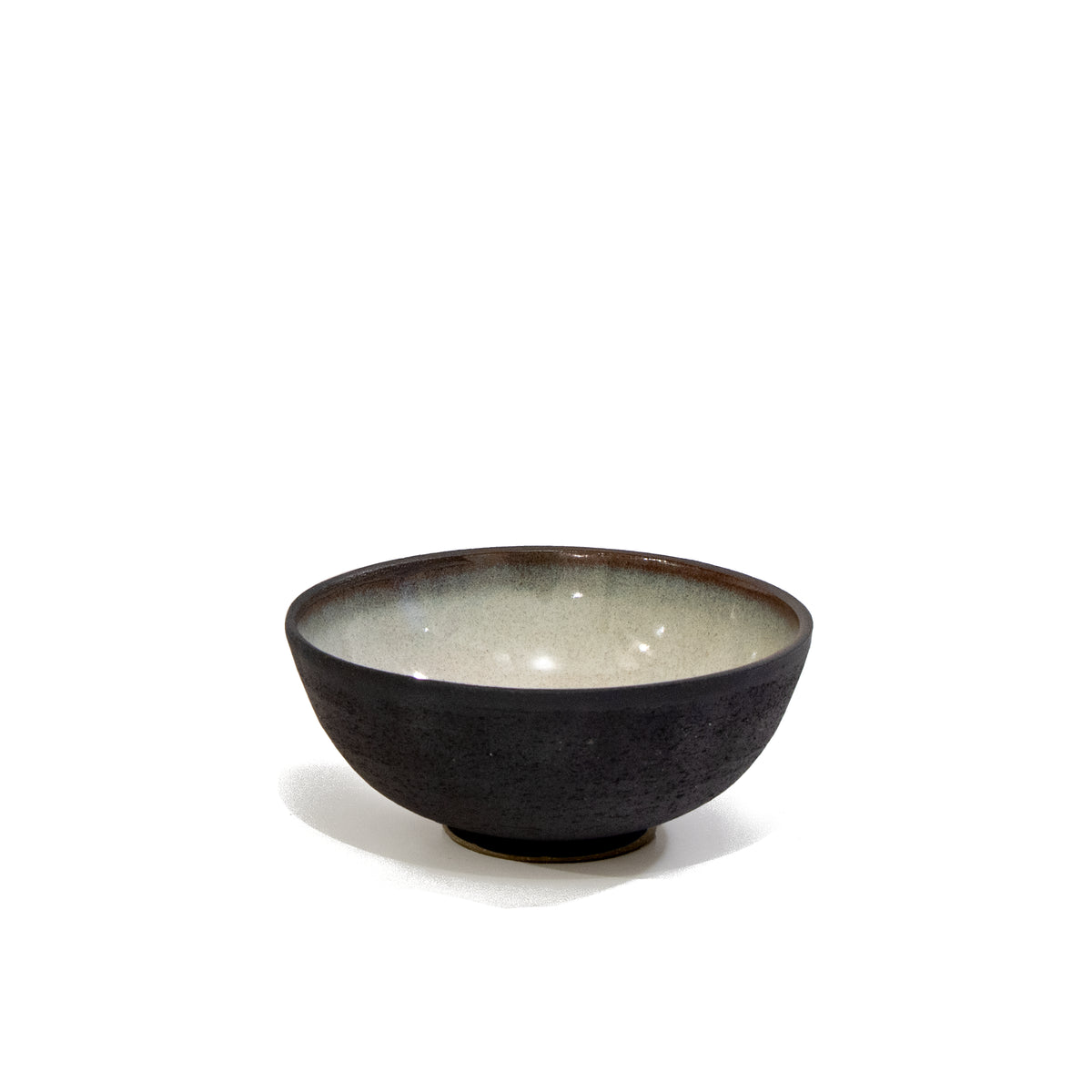 De AB Ceramics Mini Kom Zwart Opaal D10,5 is een kleine handgemaakte steengoed schaal met een donkere textuur aan de buitenkant en een gladde lichte binnenkant - ideaal voor fans van uniek servies. Van AB Ceramics, afgebeeld tegen een effen witte achtergrond.