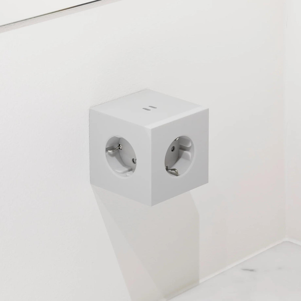 Een Avolt Square 2 USB-C Stekkerdoos Gotland Grijs, een grijze stekkerdoos van Avolt, is gemonteerd op een witte muur boven een wit aanrechtblad.