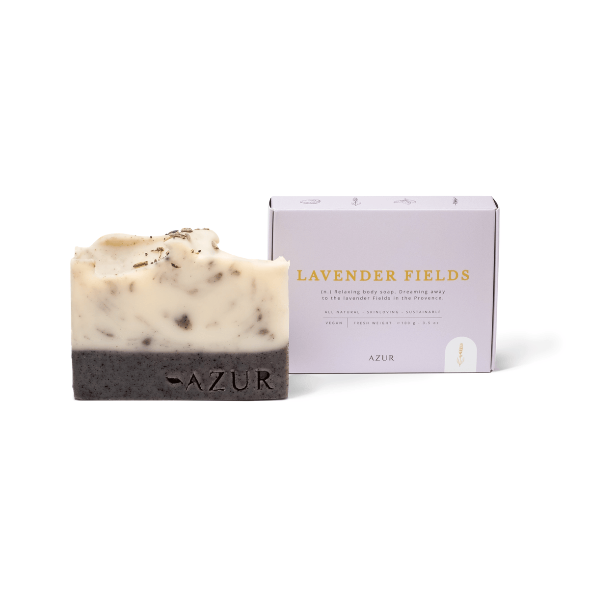 Een Azur Lavender Fields Natuurlijke Zeep Bar zit bij zijn doos, die is voorzien van gouden letters. De gemarmerde crèmelaagjes en donkere laagjes met lavendel bovenop bieden aromatherapie voor een ontspannende douche, trouw aan het merk Azur.