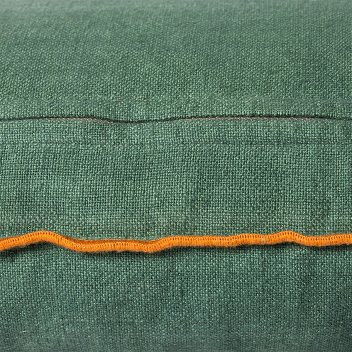Close-up van het HK Living Kussen Country House Groen 60/35, met groene stof, een zichtbare naad en een oranje zigzagsteek langs de onderrand. De grove, geweven textuur geeft dit HK Living kussen een uniek karakter.