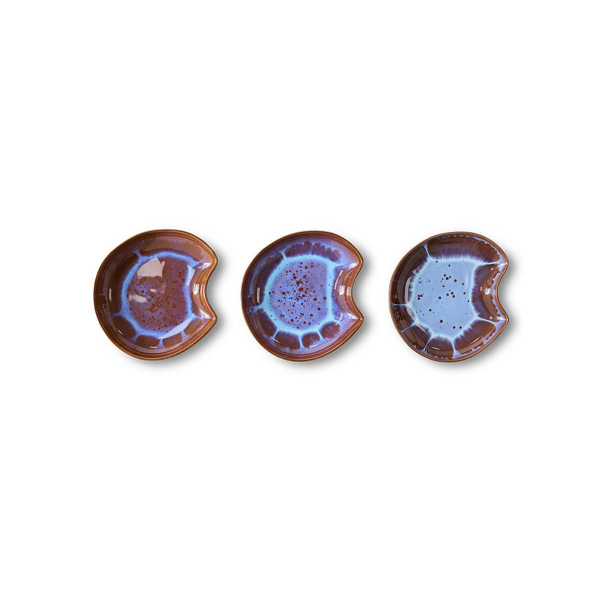 Drie HK Living Shell Schaal Sienna keramiek kommen van HK Living, klein en rond met blauw-paars geglazuurde centra, bruine randen en een hapvormige inkeping aan een kant, tentoongesteld in een rij op een witte achtergrond.