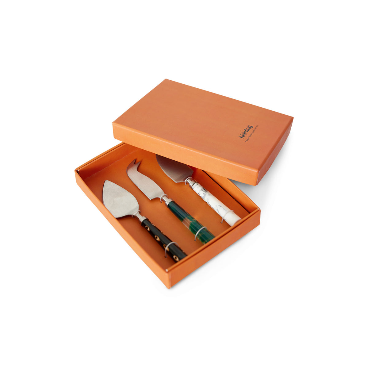 De HK Living Kaasmesjes Kust 3 st. set bestaat uit drie kaasmessen, elk met een uniek zwart, groen of wit handvat, gerangschikt in een oranje HK Living doos-ideaal voor het serveren op je favoriete kaasplank.