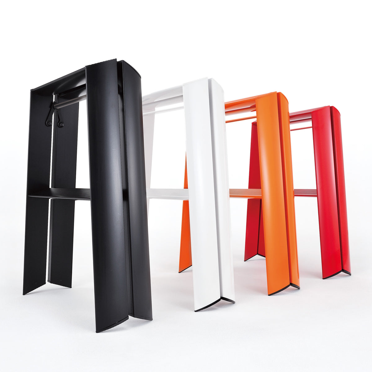 Drie moderne Hasegawa Lucano Ladder 2 Step krukken in zwart, wit en rood-oranje staan in een rij op een witte achtergrond, met brede platte poten en strakke lijnen geïnspireerd op Japanse ontwerpprincipes.