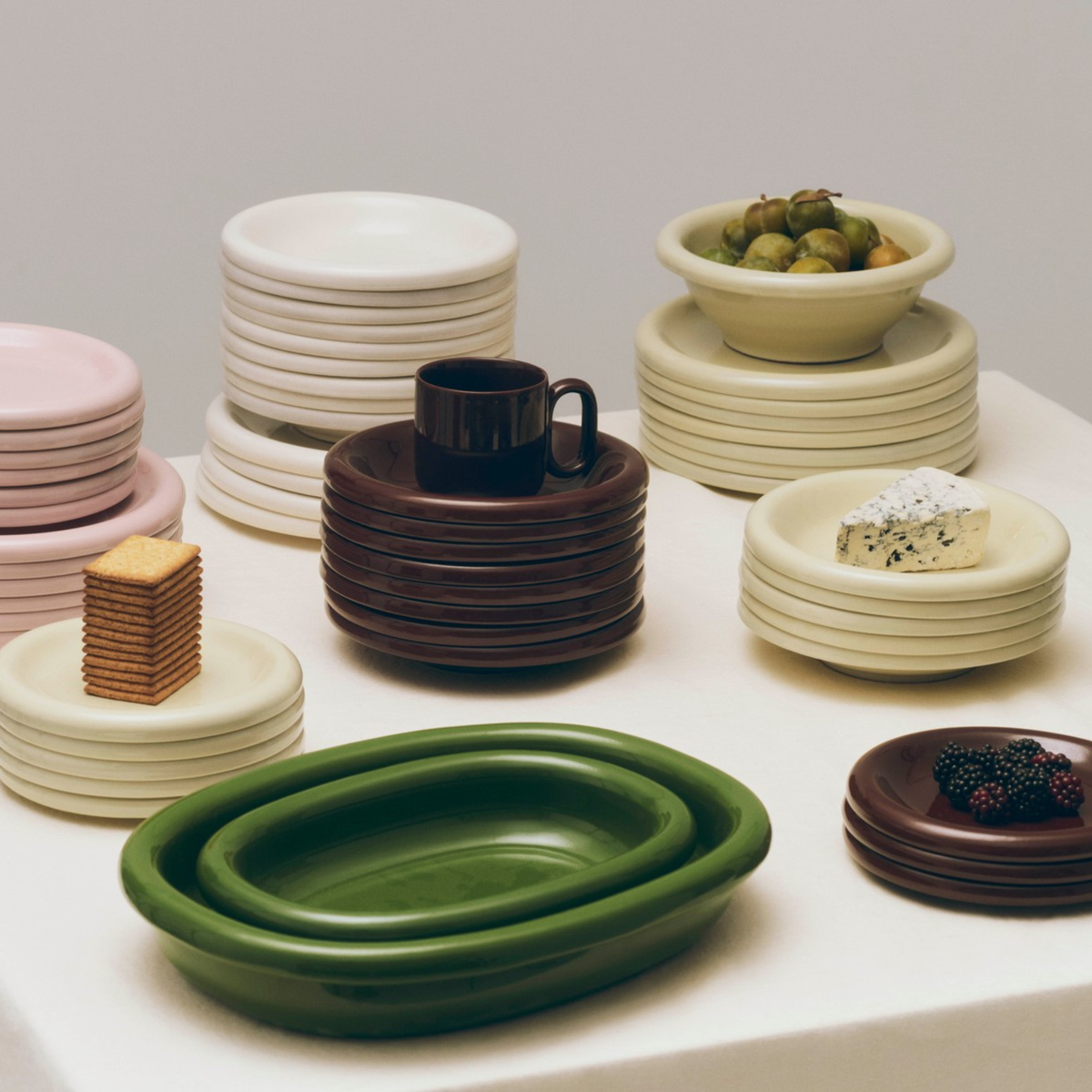Hay Barro Borden Bordeaux D18 borden van Hay, in gedempte kleuren zoals groen, bruin, wit, roze en terracotta bordeaux, zijn gestapeld op een tafel en belegd met crackers, kaas, druiven en bramen. Set bestaat uit 2 stuks.