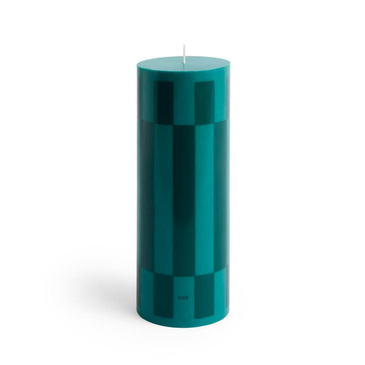 Een hoge, cilindervormige donkergroene Hay Column Kaars Donkergroen H25 kaars met subtiele verticale patronen, een gecentreerde witte lont en het HAY merk gedrukt bij de voet - een opvallend decoratief stuk voor elke ruimte.