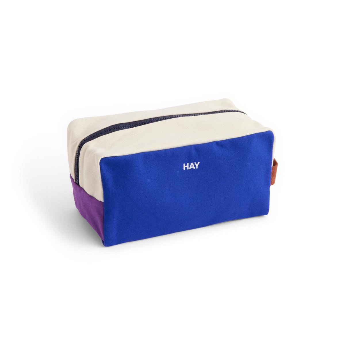 De Hay Multi Toilettas Medium Blauw van Hay is een rechthoekige tas van biologisch katoen met een crèmekleurige bovenkant, blauwe voorkant met "HAY" print, paarse zijkanten, bruine lus en zwarte rits - ideaal voor het opbergen van cosmetica. Afgezet tegen een witte achtergrond.
