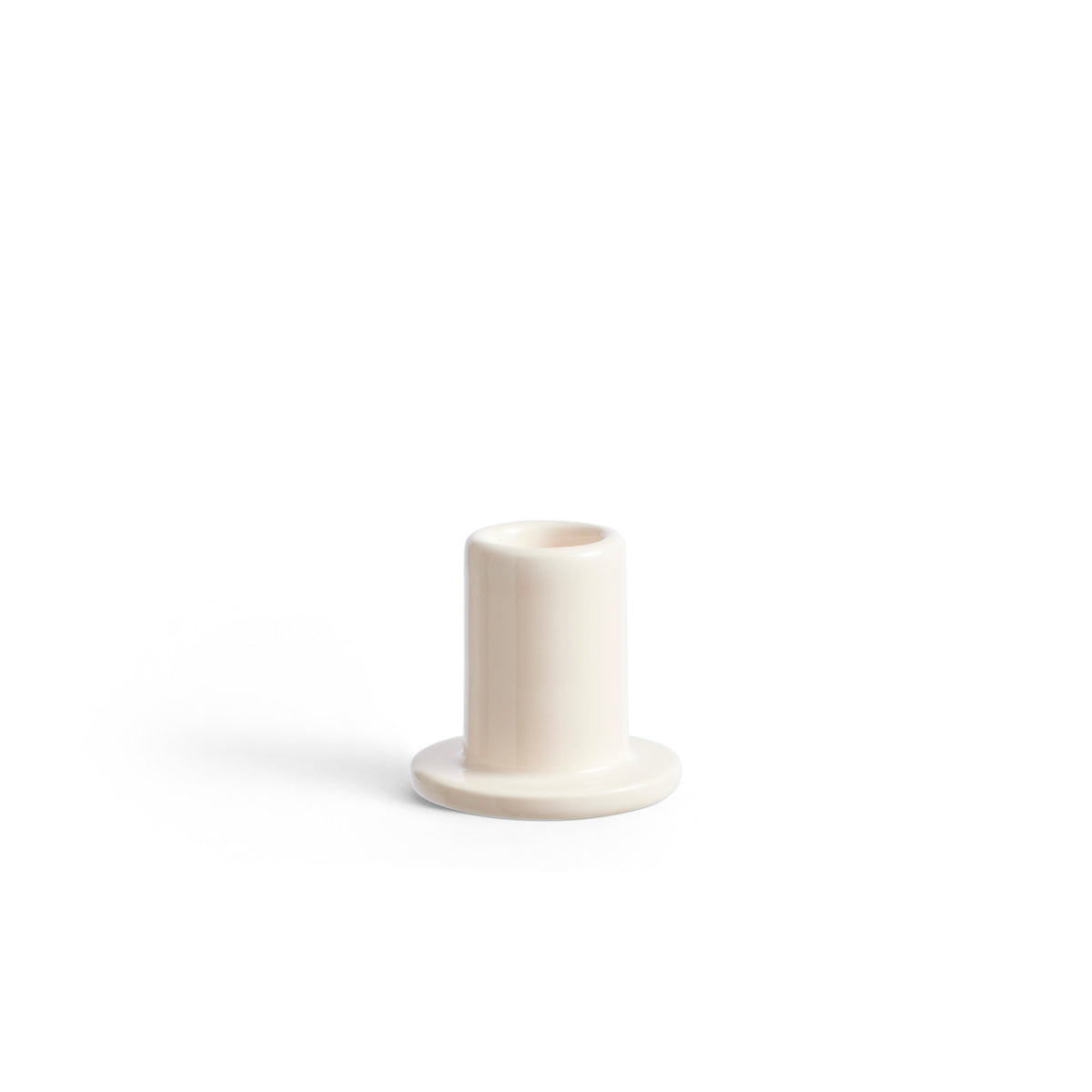 De Hay Tube Kandelaar Off-White van Hay heeft een kleine, cilindrische vorm en een brede basis met een minimalistisch ontwerp, tegen een effen witte achtergrond.