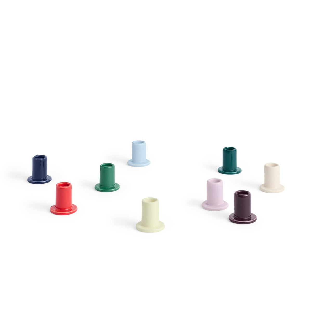 Acht kleine Hay Tube Kandelaar kandelaars van Hay, elk met een uitlopende voet, worden weergegeven op een witte achtergrond in rood, blauw, groen, crème, lichtgeel, paars en bordeaux.