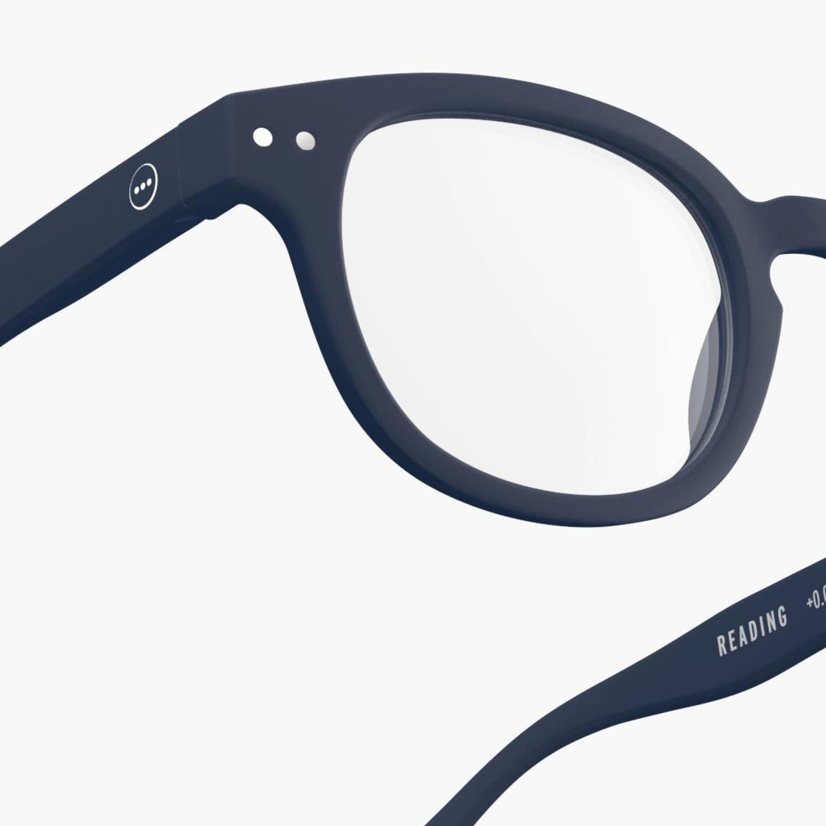 Close-up van de Izipizi Leesbril #C Navy, met ronde glazen en donker montuur. Op de binnenste arm staat de tekst READING +0,0. Dit Izipizi leesbril staat op een effen witte achtergrond.
