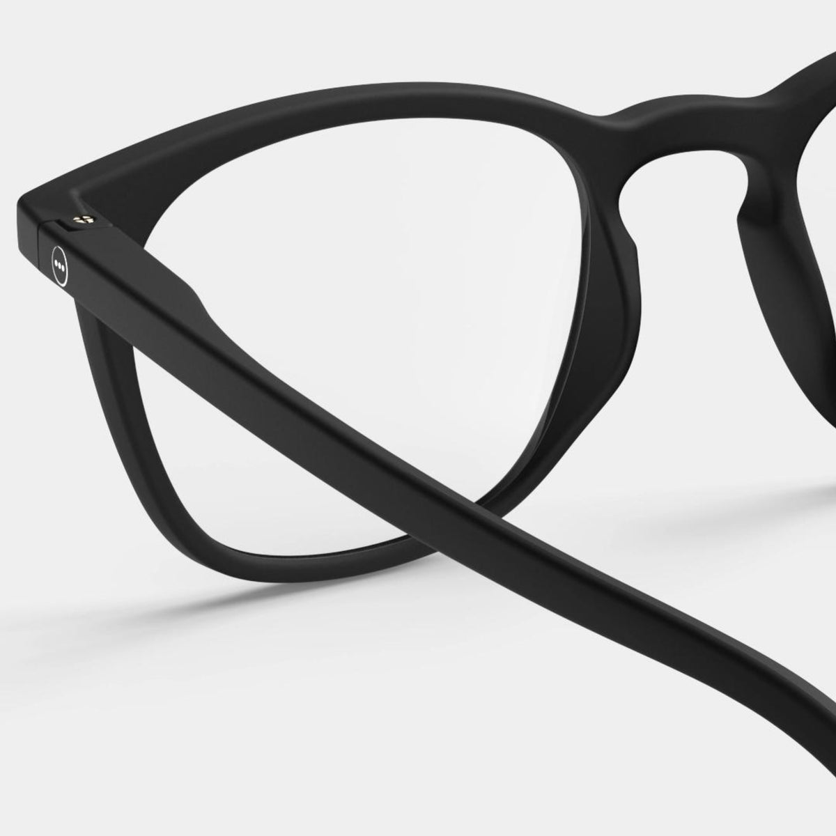 Close-up van de Izipizi Leesbril #E Zwart van Izipizi met een zwart montuur en heldere glazen, met de nadruk op de slapen en het scharnier om het moderne ontwerp van deze unisex leesbril tegen een effen witte achtergrond te benadrukken.