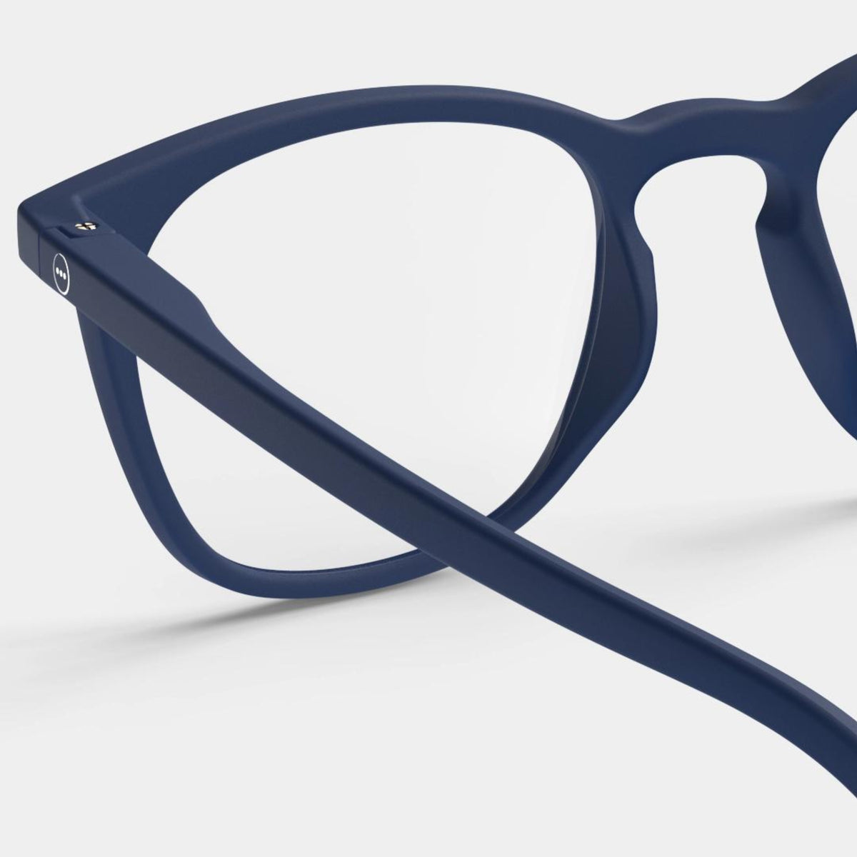 Close-up van Izipizi Leesbril #E Navy bril, met donkerblauw montuur met een zichtbare zijarm en lens tegen een effen lichte achtergrond.