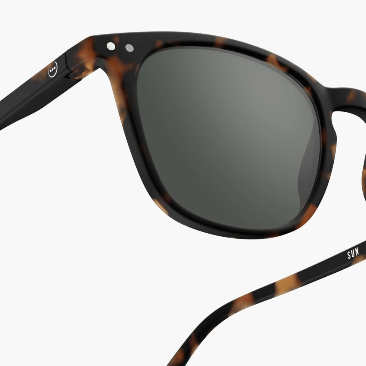 Close-up van de Izipizi Zonnebril Sterkte #E Tortoise van Izipizi met donkere glazen en een smiley embleem op de slapen, biedt UV-bescherming voor stijlvol unisex dagelijks gebruik tegen een witte achtergrond.