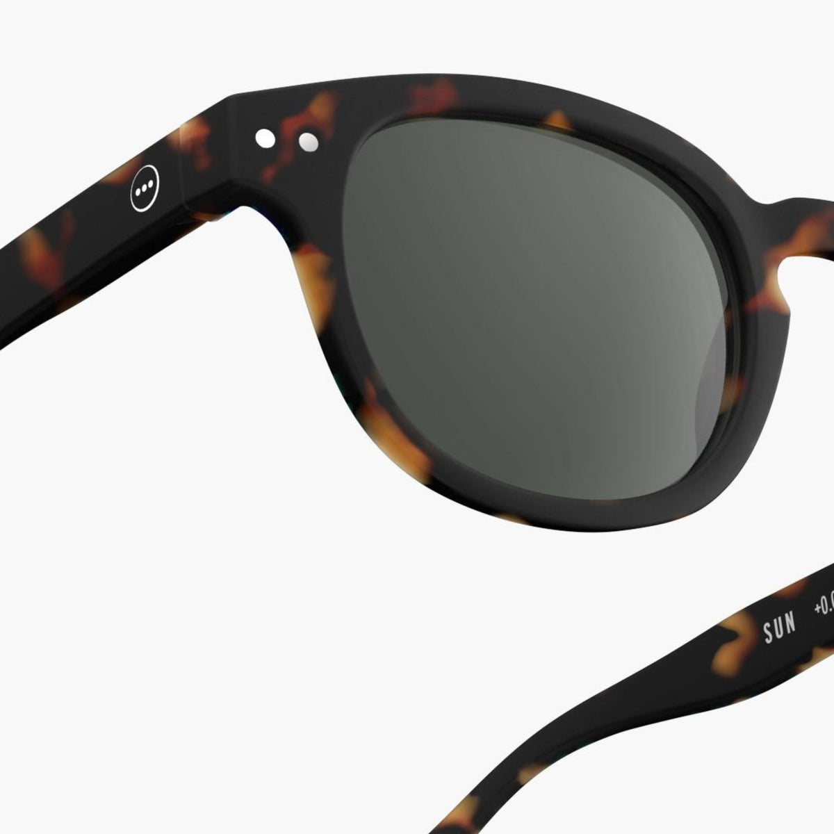 Close-up van Izipizi Zonnebril #C Tortoise van Izipizi, met ronde donkere glazen, een wit logo op de arm en UV-bescherming, tegen een effen witte achtergrond.