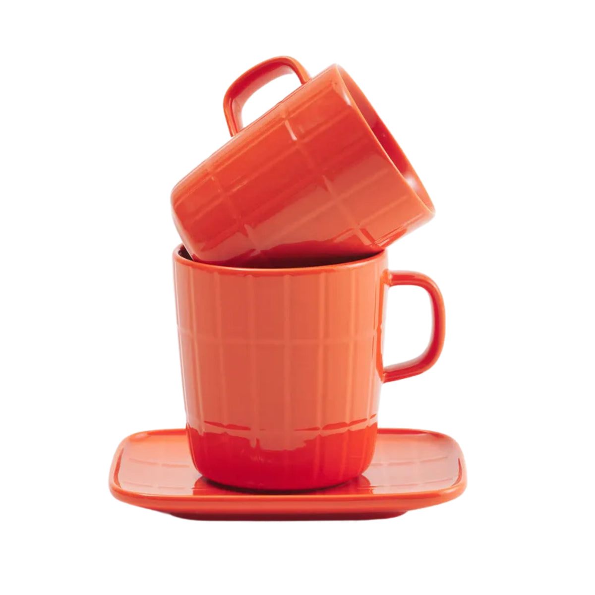 Twee oranje Marimekko Oiva Tiiliskivi mokken, de ene schuin in de andere genesteld, rusten op een bijpassende Marimekko Oiva Tiiliskivi Bord Oranje 15/12. Beide hebben een subtiel rasterpatroon tegen een witte achtergrond.