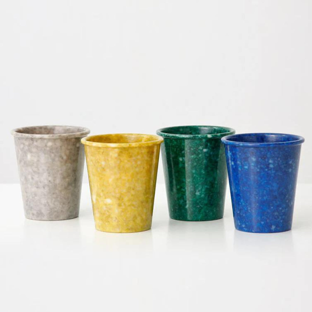 Vier Melamine Marbled Beker Navy bekers van Melamine Marbled staan naast elkaar op een wit oppervlak tegen een effen achtergrond - ideaal als kleurrijke bureau-organizer.