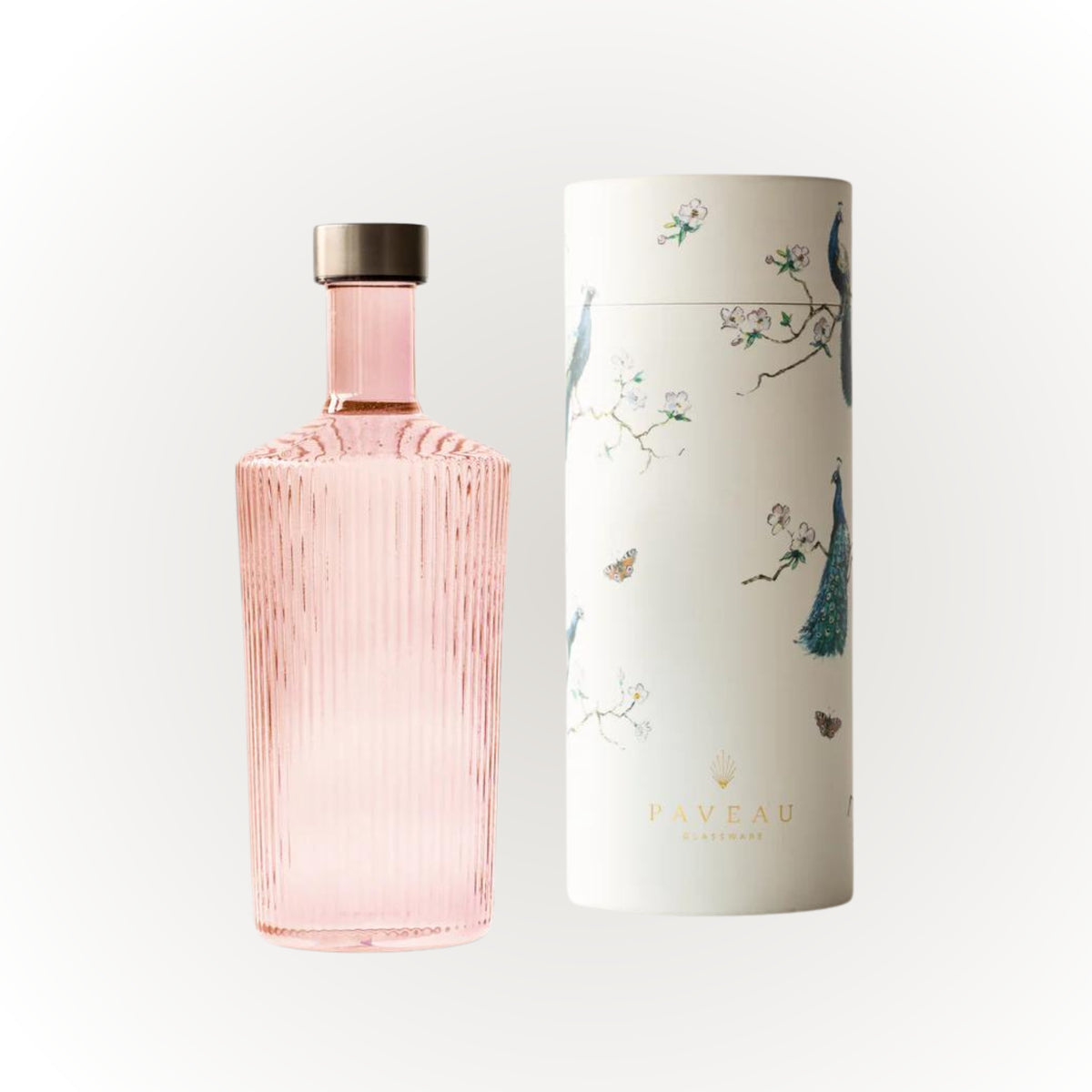 De Paveau Waterfles Pink 1,25 l met geribbeld design en metalen dop staat naast zijn witte cilindrische doos, versierd met illustraties van pauwen, takken en vlinders en de merknaam Paveau.