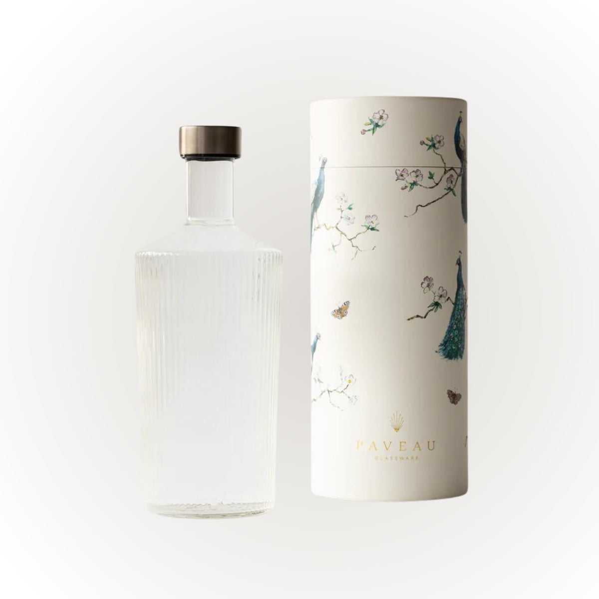 Een heldere, elegante Paveau Waterfles White Haven 1,25 l met een metalen dop staat naast een cilindrische doos versierd met pauwen en vlinders. Beide, met het merk Paveau, staan tegen een effen witte achtergrond.