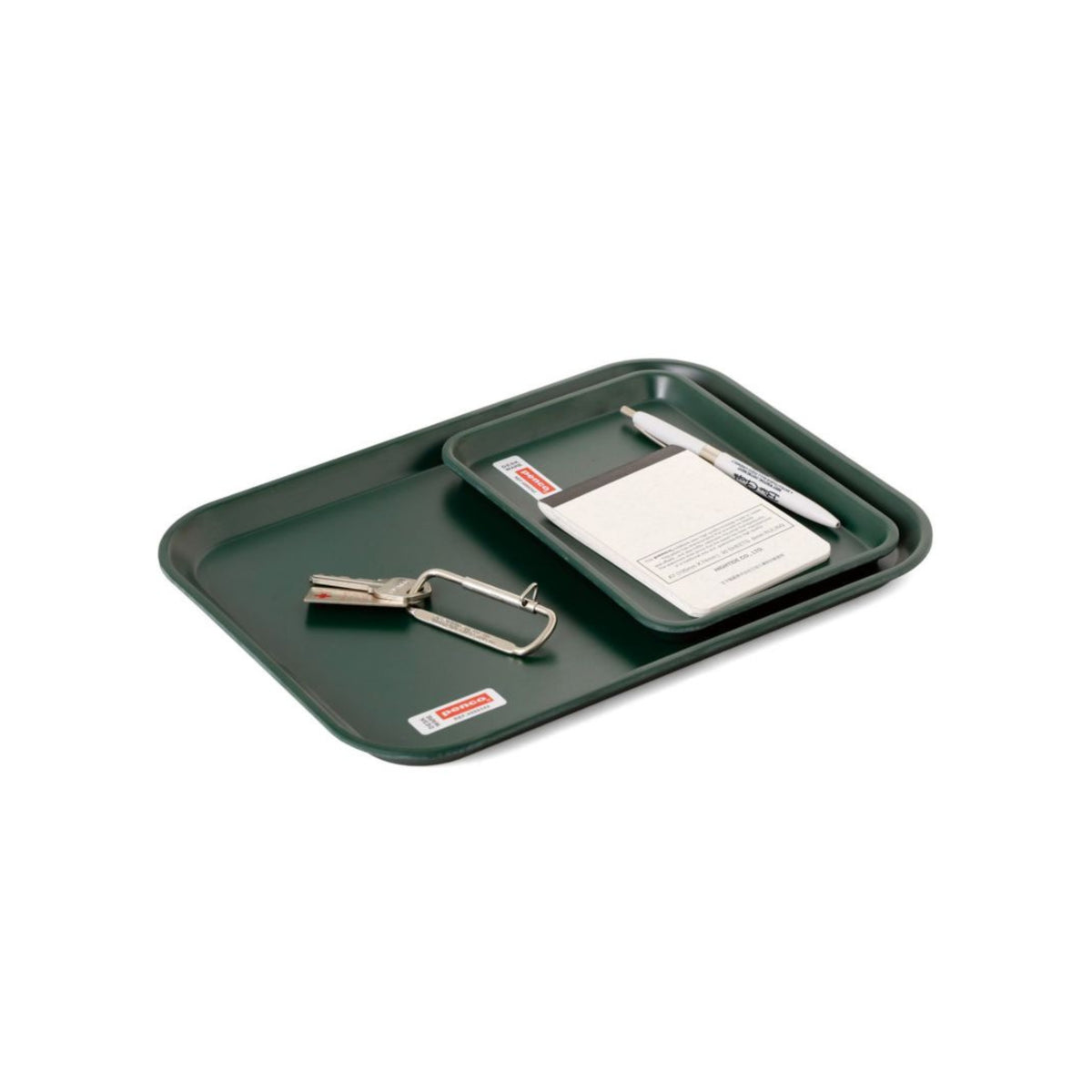 Twee Penco Dienblad Donkergroen 28/21 dienbladen van het merk Penco, één kleiner in de andere geplaatst, vormen een veelzijdig bureau-accessoire met een karabijnhaak met sleutels, pen en notitieblok.