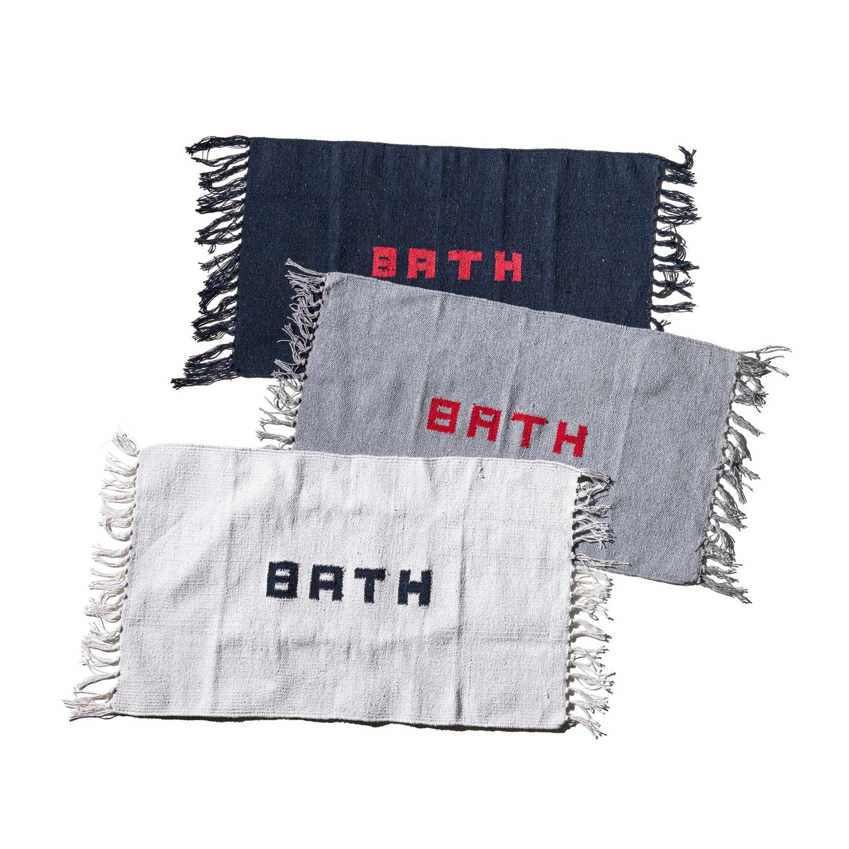 Drie Puebco Badmat Gerecycleerd Garen Blauw 75/45 matten, handgeweven in marineblauw, grijs en wit met franjeranden en "BATH" erop geweven, liggen verspringend op een witte achtergrond.