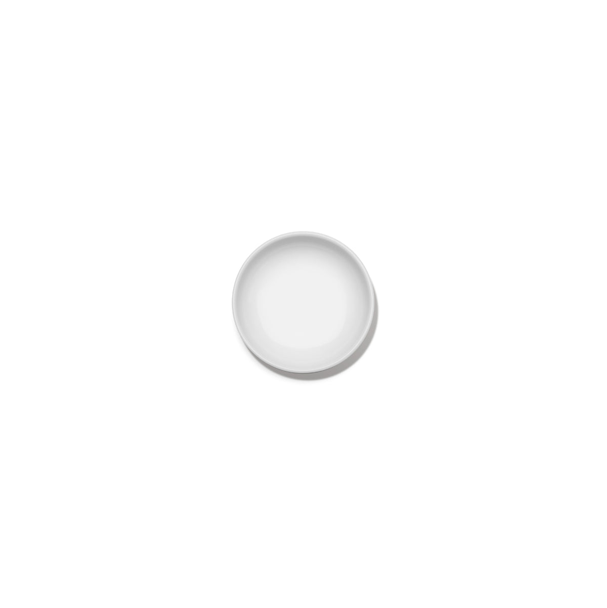 Een minimalistisch, klein, rond bord Serax Base Laag Bord D8 van Serax is gecentreerd op een effen witte achtergrond en van bovenaf bekeken. Het bord is leeg en heeft een elegant, eenvoudig ontwerp.
