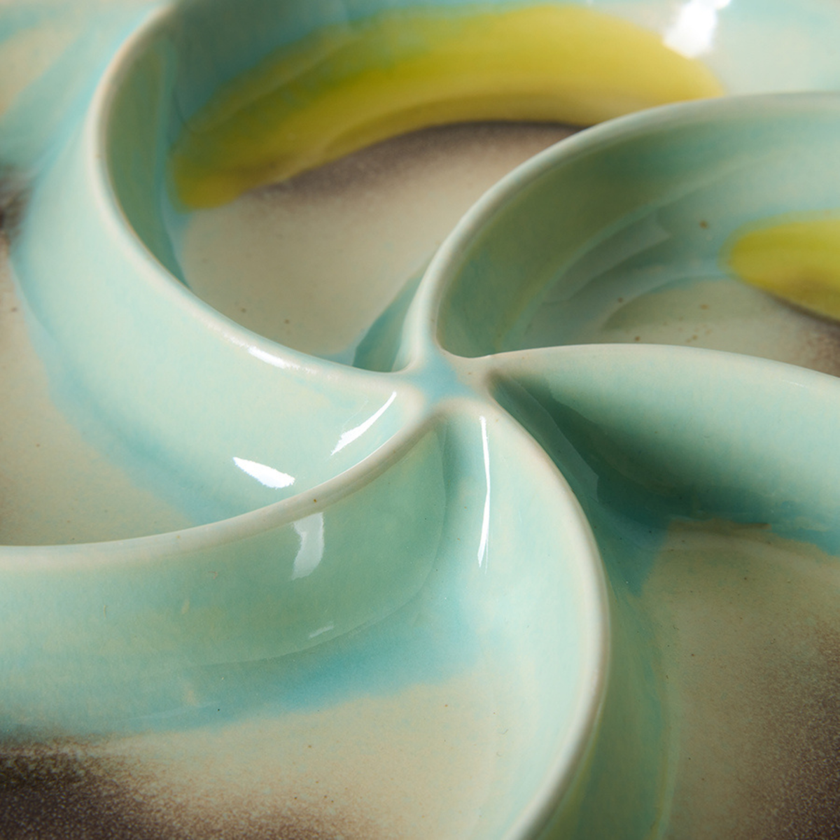 Close-up van de HK Living 70s Ceramics Snack Schaal Glint, met vier afgeronde delen geglazuurd in licht turquoise, geel en beige voor een gladde, glanzende jaren 70-geïnspireerde look.