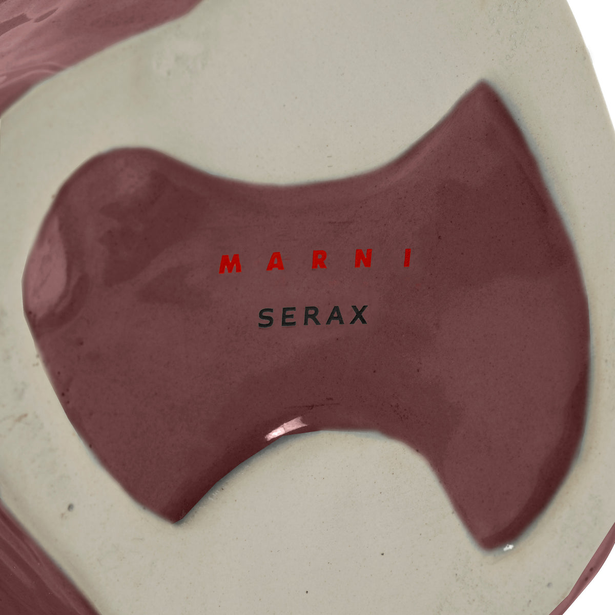 Close-up van de basis van een Serax Marni After Midnight Uil Vaas Aubergine XS, met glanzende kastanjebruine en crèmekleurige tinten. "MARNI" in rood en "SERAX" in zwart zijn op het oppervlak gedrukt.
