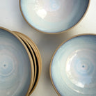 Drie AB Ceramics Noodle Kom Geel Opaal D19 kommen, met een lichtblauw en wit geglazuurde binnenkant en natuurlijk kleibruine buitenkant, staan op een wit oppervlak - ideaal voor noedels of het serveren van handgemaakte servies.