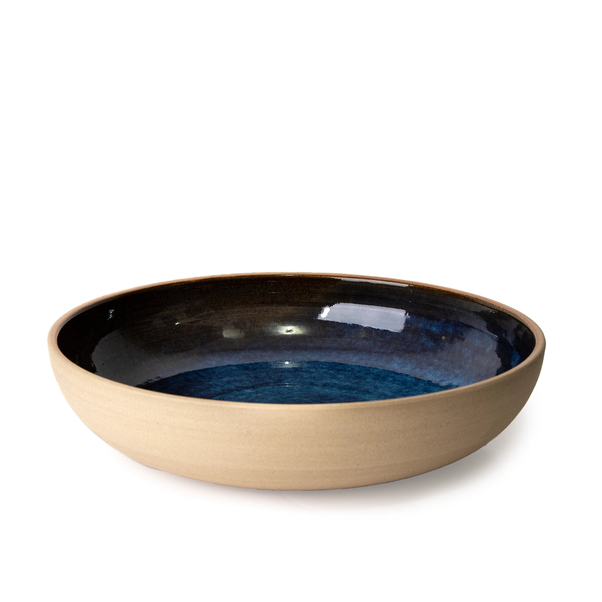 De AB Ceramics Serveerschaal Geel Blauw D25 is een handgemaakte, ondiepe ronde schaal van gele steengoed klei met mat beige buitenkant en glanzend donkerblauw interieur, van het merk AB Ceramics, gefotografeerd tegen een witte achtergrond.