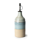 De AB Ceramics Olijfolie Fles Ribbel Wit Opaal 45 cl is een handgeblazen olijfolie fles van keramiek met een beige basis, lichtblauw midden, geribbelde witte bovenkant, metalen tuit en zwarte dop van AB Ceramics.