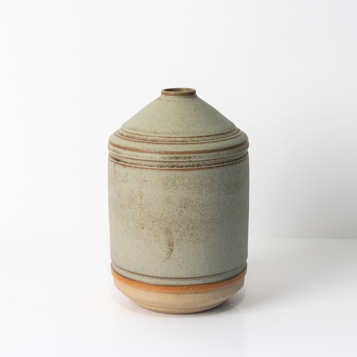 De AB Ceramics Olijfolie Fles Wit Mos 55 cl is een ronde, lichtgrijze keramieken fles met smalle opening en bruine lijnen, ideaal als stijlvolle keukenaccessoire en getoond tegen een witte achtergrond.