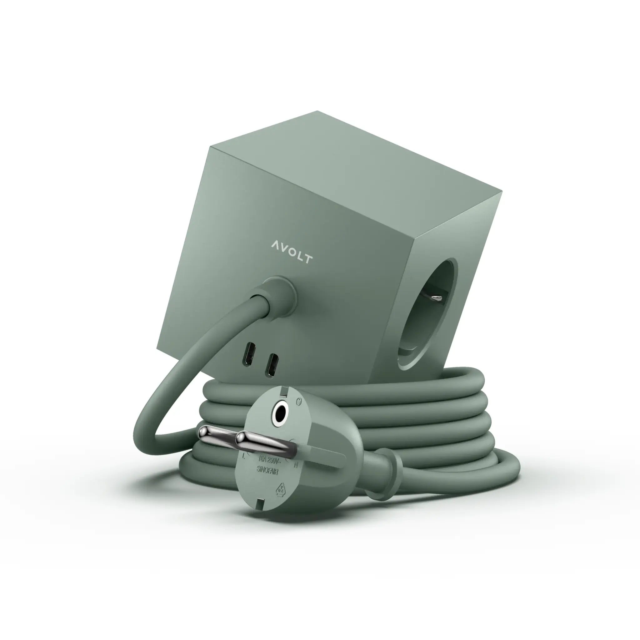 De Avolt Square 1 USB-C Stekkerdoos Eik Groen 1,8 m is een minimalistische groene kubusvormige stekkerdoos met meerdere stopcontacten en een lang spiraalsnoer, afgebeeld tegen een witte achtergrond.