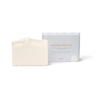 De Azur Sauna Feels Natuurlijke Scrub Zeep Bar zit naast zijn minimalistische witte doos met gouden en grijze accenten en benadrukt zijn zout eucalyptusmengsel als een verfrissende eucalyptus lichaamszeep.