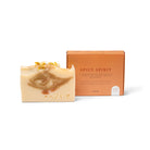 De Azur Spicy Spirit Natuurlijke Zeep Bar, handgemaakt in bruine en crèmekleurige swirls, ligt naast een oranje doos van Azur. Verrijkt met kurkuma en gedroogde bloemblaadjes voor een warme, natuurlijke uitstraling.