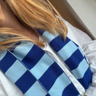 Een persoon met lang blond haar, in een wit shirt en een Caro Sjaal Ace Ice Ice Baby van Caro Antwerp, vanaf de schouders gezien.