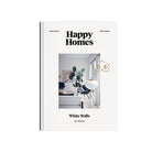 Cozy Publishing Happy Homes White Walls Boek is een lifestyle koffietafelboek met een minimalistische cover waarin een lichte, moderne woonkamer wordt getoond - ideaal voor fans van Scandinavische interieurs.