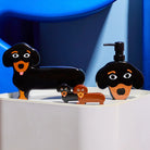 Kleurrijke Fluid Market Zout- en Pepervaatjes Teckel 2 st. en bijpassende bakjes in cartoonstijl staan op een wit oppervlak met een blauwe abstracte achtergrond - perfect als uniek designcadeau.