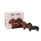 De Fluid Market Zout- en Pepervaatjes Teckel 2 st. van Fluid Market heeft twee keramieken teckels, bruin en zwart, met een doos versierd met cartoonhonden-een charmant cadeau voor hondenliefhebbers.