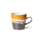 De HK Living 70s Ceramics Americano Mok Fire heeft een aardse kleurverloop met een mosterdgele bovenkant, een witte middenband, een donkerbruine onderkant en een handvat aan de rechterkant.
