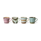 De HK Living 70s Ceramics Cappuccinokop Dada 4 st. set van HK Living bestaat uit vier mokken in unieke kleurencombinaties: roze met zwart, groen met bruin, blauw met beige en groen met spikkels, afgebeeld op een witte achtergrond.