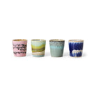 De HK Living 70s Ceramics Eierdop Vibrance 4 st. set bestaat uit vier kleine keramische kopjes in unieke glazuren - roze en zwart, geel en groen, turquoise en blauw met witte strepen - gerangschikt op een witte achtergrond.