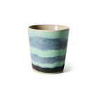 De HK Living 70s Ceramics Koffiekop heeft een glad, taps toelopend keramisch ontwerp met matgroene, donkerblauwe en bruine banden. Deze mok is geïnspireerd op de jaren 70 stijl en is verkrijgbaar op Ozon.