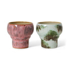 Twee HK Living 70s Ceramics Lungo Mokken Expression mokken met gestructureerd oppervlak: een roze geglazuurd met bruine accenten, de andere wit met groen. Beide hebben een brede rand, smalle voet en worden verkocht als set van twee.
