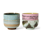Vier HK Living 70s Ceramics Noodle Kom Dada D13 kommen zijn per twee gestapeld: de linkerset in blauw en bruin, de rechterset met een groene kom met aardse patronen en een roze kom met donkere spikkels - perfecte handgemaakte kommen.