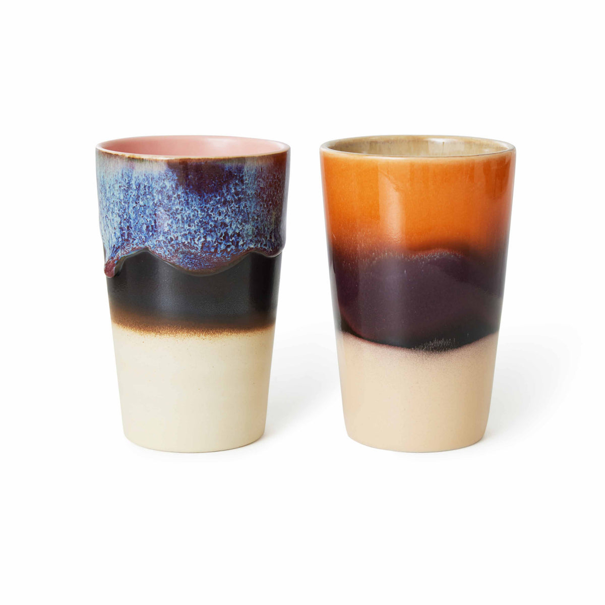 De HK Living 70s Ceramics Theekop Dusk 2 st. set bestaat uit twee hoge keramische koppen met artistiek glazuur: de ene met een golvende blauwpaarse rand, de andere in glad oranjebruin, beide met een beige basis en retro stijl tegen een witte achtergrond.