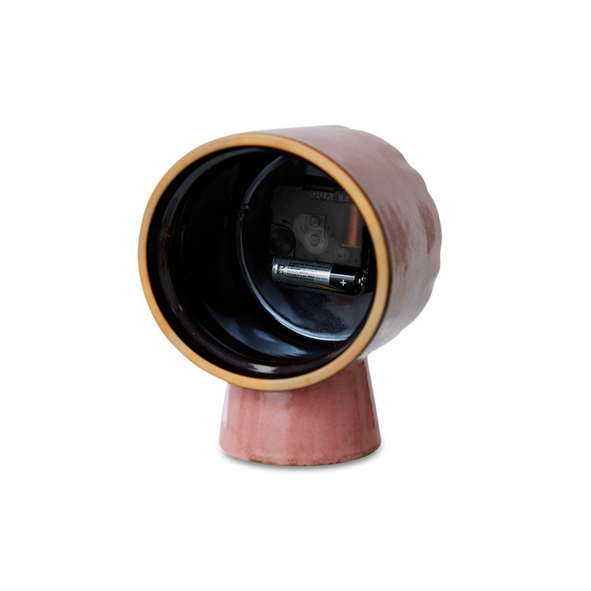 De HK Living Retro Klok Roze van HK Living heeft een ronde, holle bovenkant en een cilindrische voet; hij staat rechtop en heeft een open achterkant waardoor een vakje zichtbaar is voor een AA-batterij en het uurwerk.