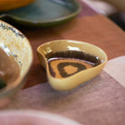Een HK Living Shell Tapas Kom Triffle, met een bruin en geel patroon, staat op een geruit tafelkleed naast andere HK Living tapas kom schotels.