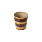 De HK Living 70s Ceramics Koffiekop Cliffs heeft een keramische constructie met een lichtbruine basis en twee donkerbruin geglazuurde banden, die een retro look creëren tegen een frisse witte achtergrond.
